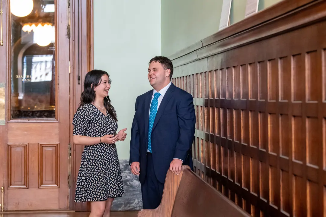 Two pre-law students stand and converse in the historic county courthouse in professional attire