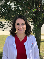 Photo of nursing student in red scrubs and white lab coat