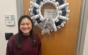 Student standing in front of a wreath made from ultrasound gel bottles