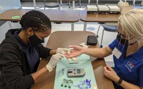 Student using needle to prick finger