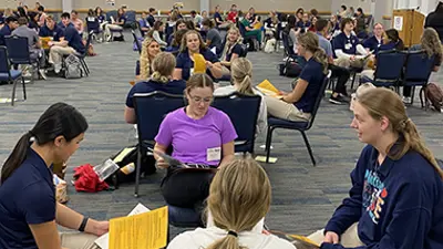 Health professions students sit in small groups in Carter Hall for an interprofessional education program on poverty