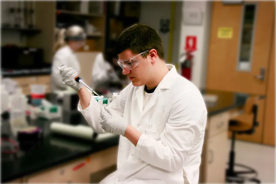 Male student uses a pipette to fill small tubes with liquid in a genetics lab