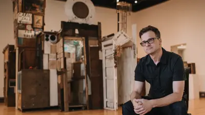 USI art and design alumnus Kevin Titzer poses with his sculptures made of found objects