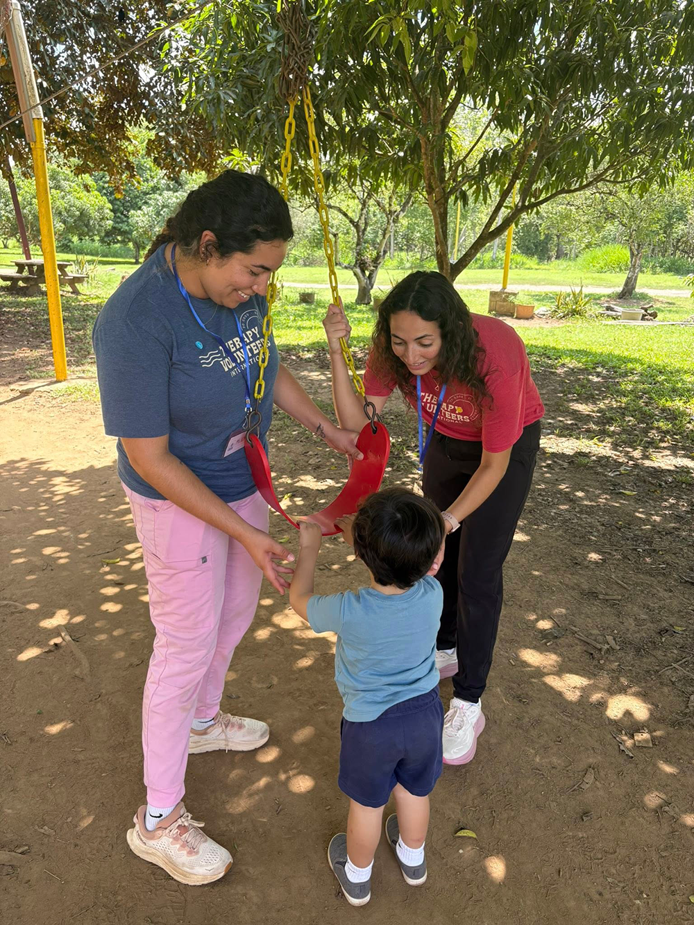 Two OT students help a child get into a swing