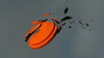 The clay target is shattered, with several large shards and dozens of smaller black fragments exploding outward