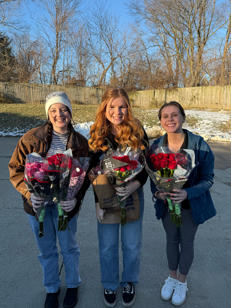 Students holding roses they are giving to nursing home residents