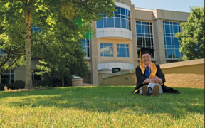 USI psychology student in cap and gown on the lawn in front of the Liberal Arts Center