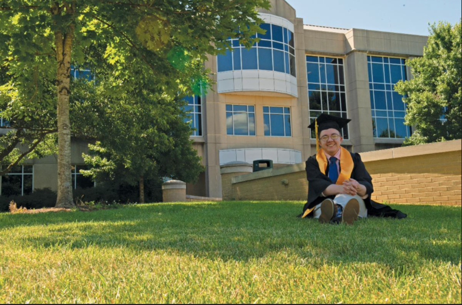USI psychology student in cap and gown on the lawn in front of the Liberal Arts Center