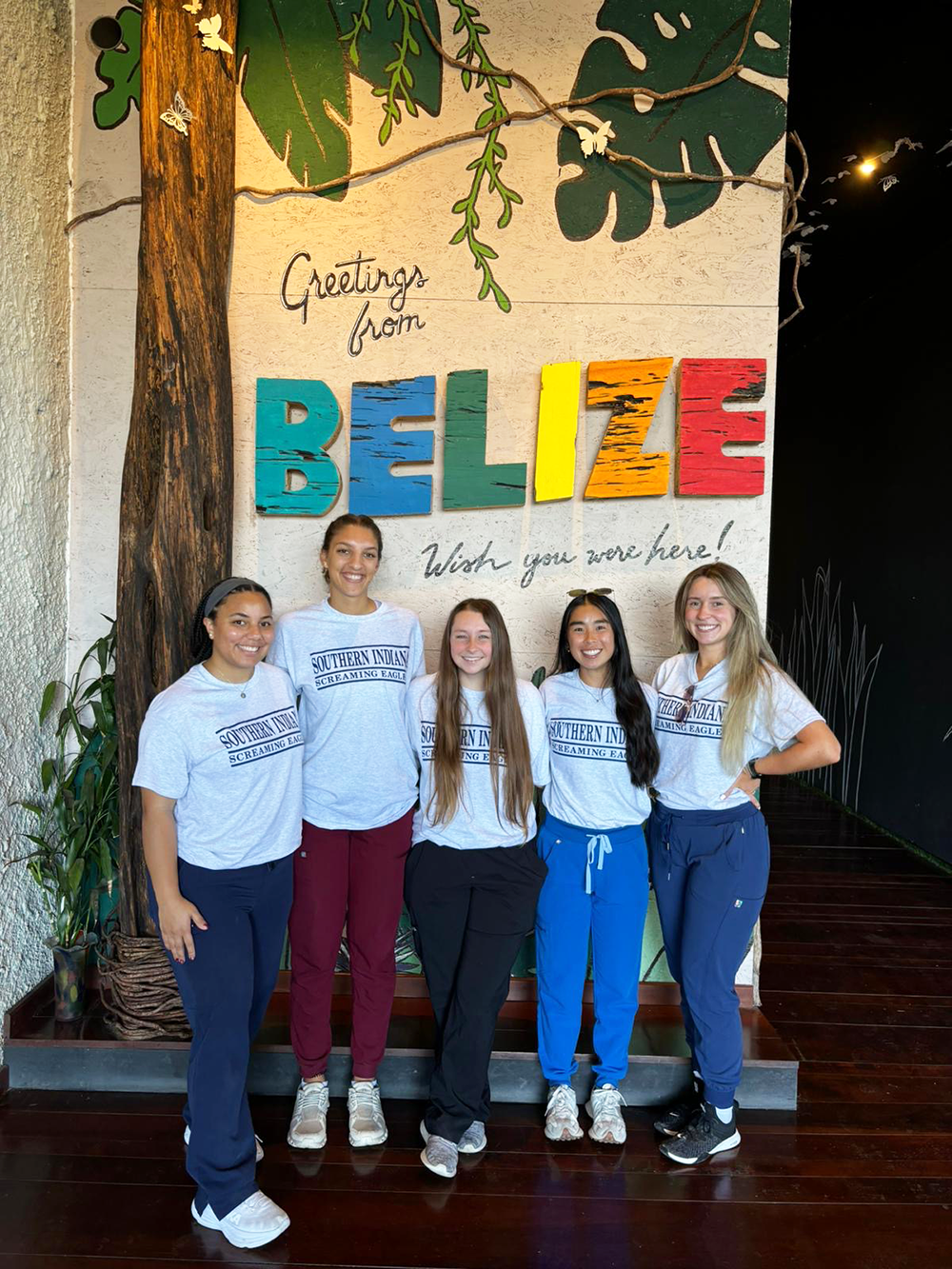 OT students in front of a sign that says "Welcome to Belize."