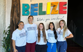 OT students in front of a sign that says "Welcome to Belize."