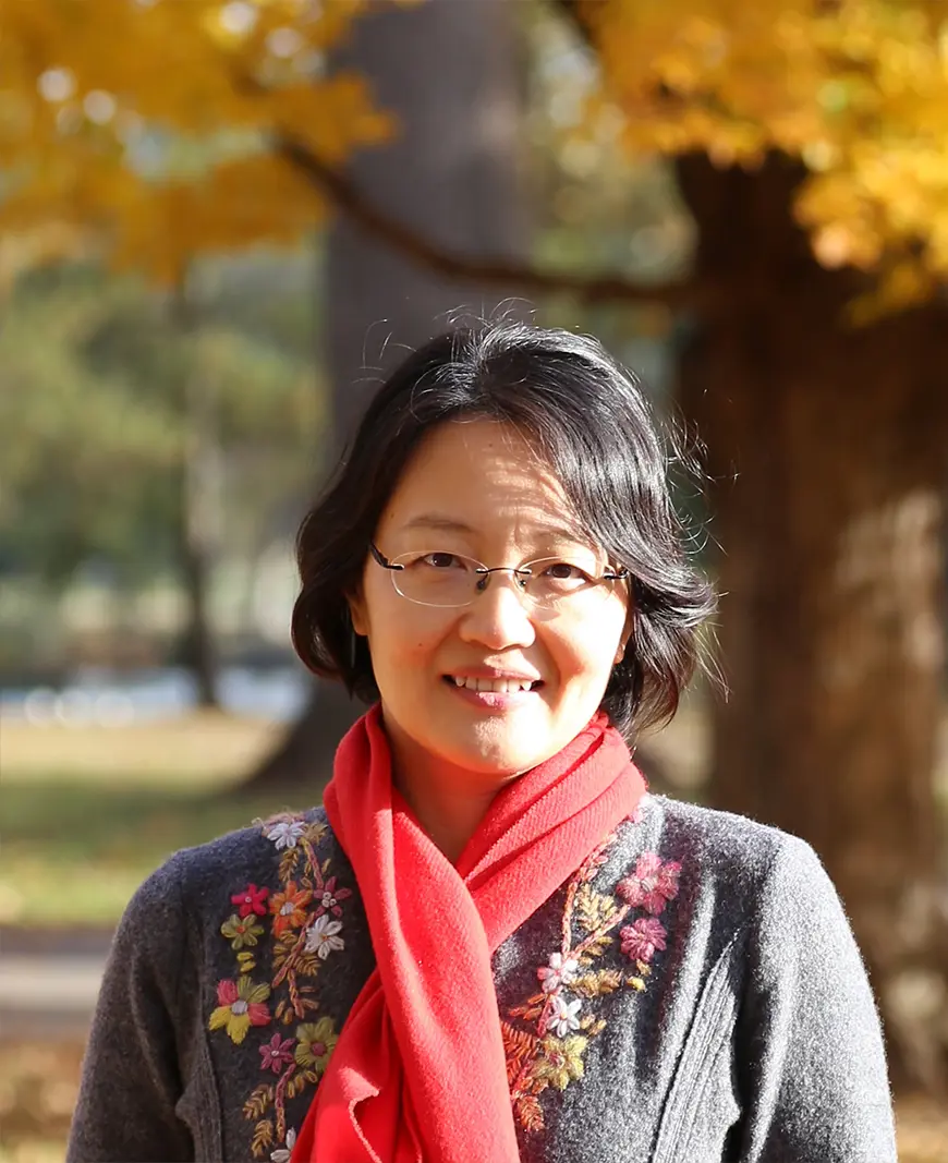 Xinran Hu in front of trees with fall foliage