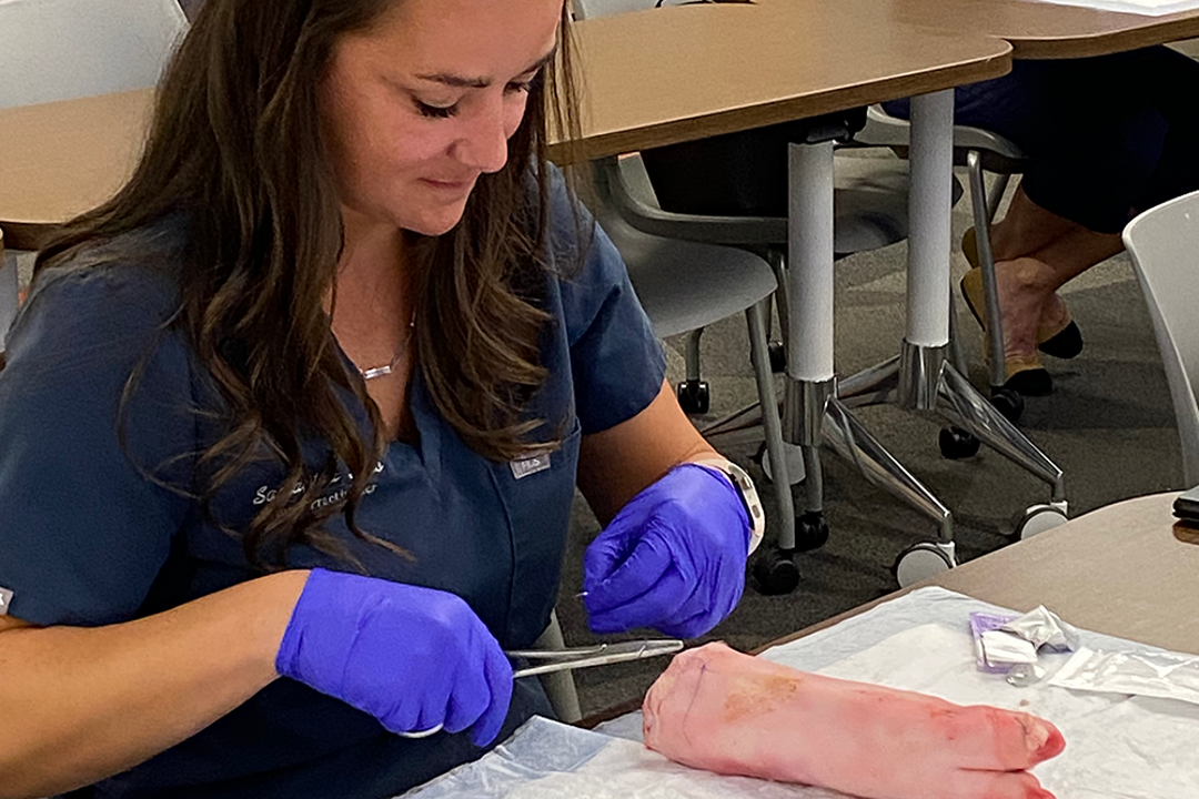 Woman practicing suturing on a pig hoof