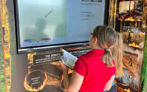 Students explore an interactive exhibit about prescribed burns and wildfire management.