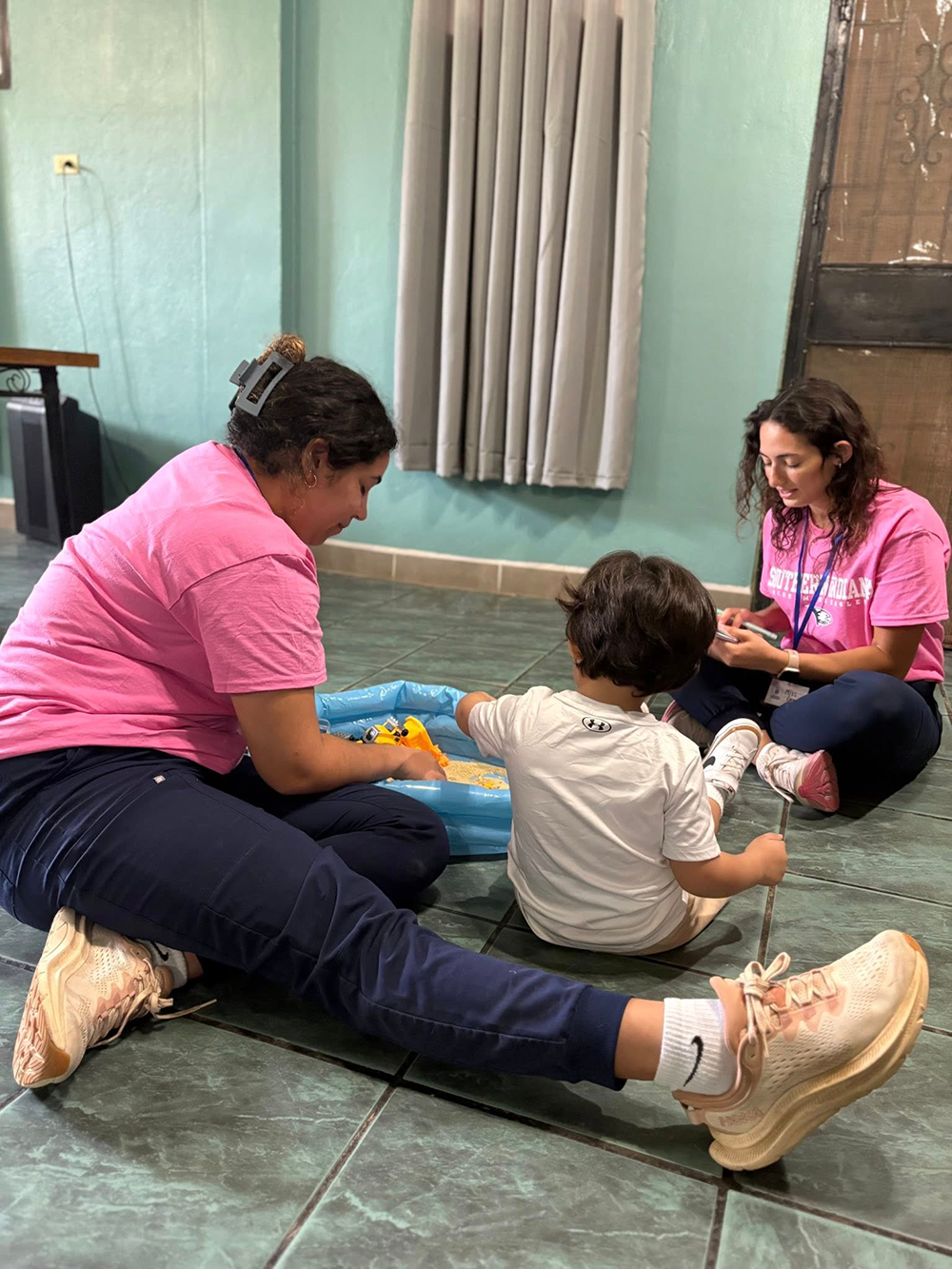 OT students sitting on the floor with a child