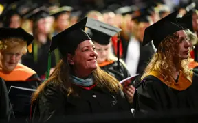 Photo of USI faculty member in regalia smiling during commencement ceremony