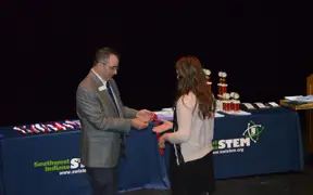SwISTEM staff member engages with the public at a conference table with a SwISTEM logo
