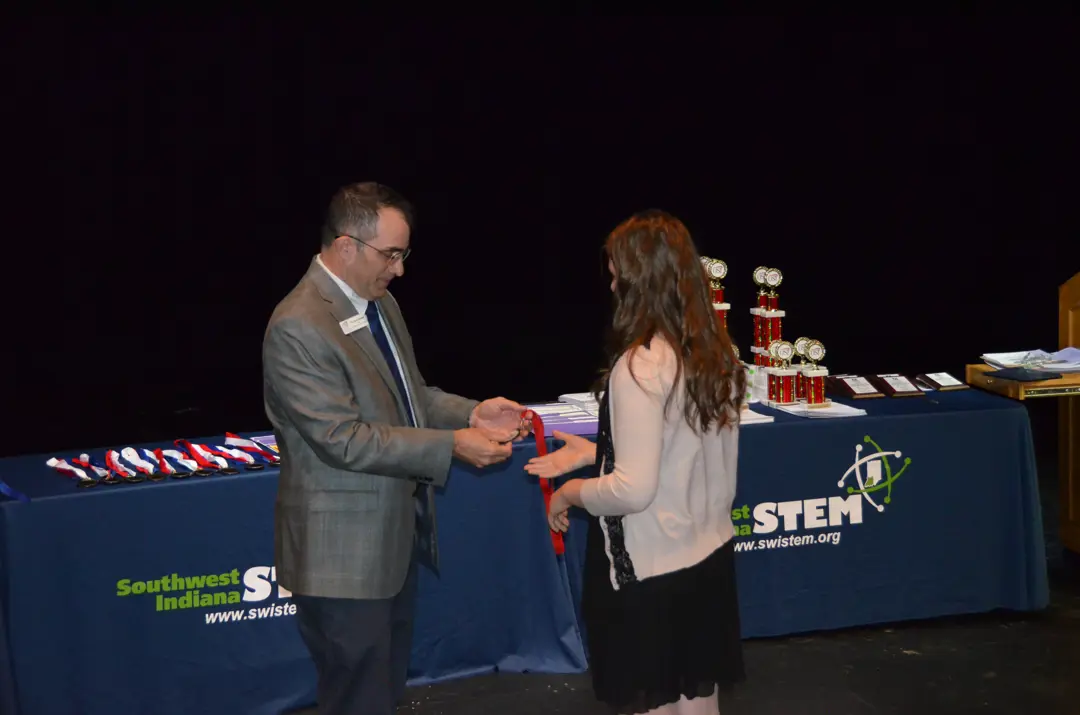 SwISTEM staff member engages with the public at a conference table with a SwISTEM logo