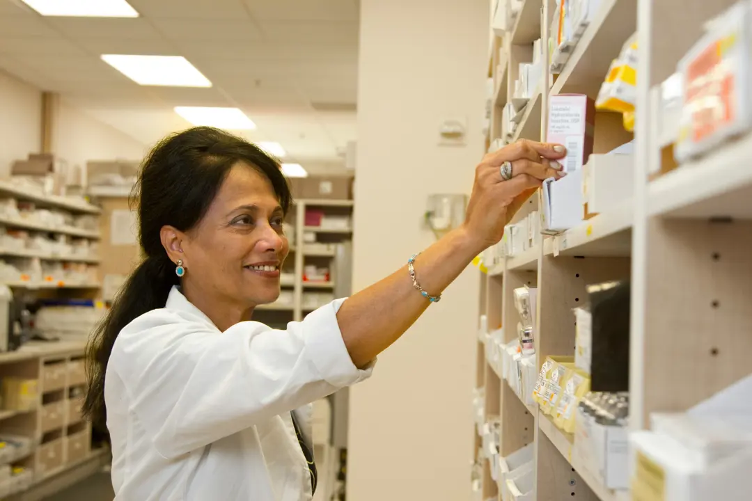 Pharmacy technician organizes prescriptions on a pharmacy shelf
