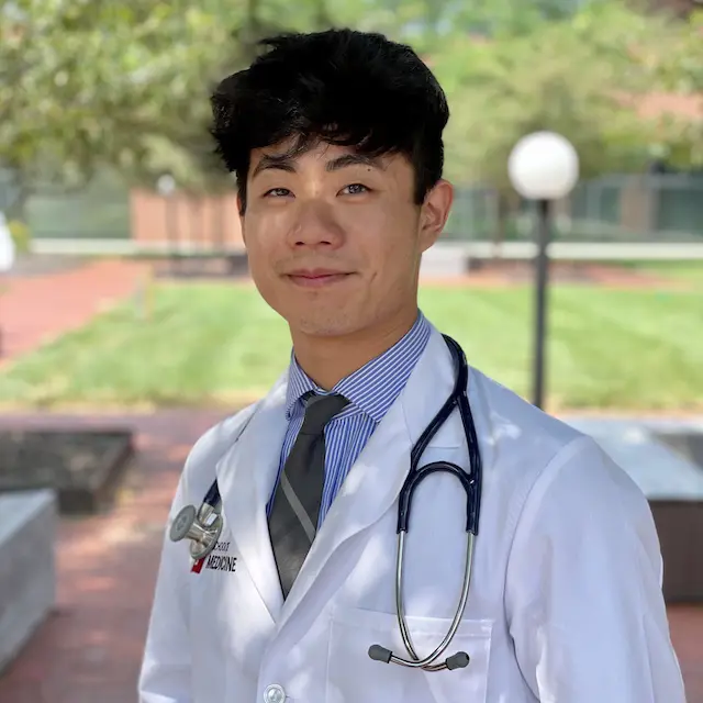 USI pre-medicine student Adam Zhuang in a white lab coat with a stethoscope