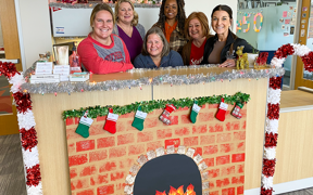 employees stand behind a desk decorated for the holidays