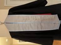 white stole with light blue trim and gold lettering that reads USI Art Club on one side
