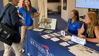 Student volunteers for the Bronstein Center speak with a visitor at an informational table