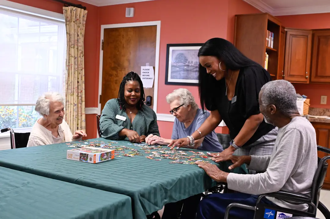 Two women working a puzzle with residents at a nursing home