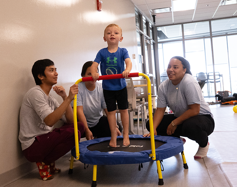 Child on a small trampoline with OT students