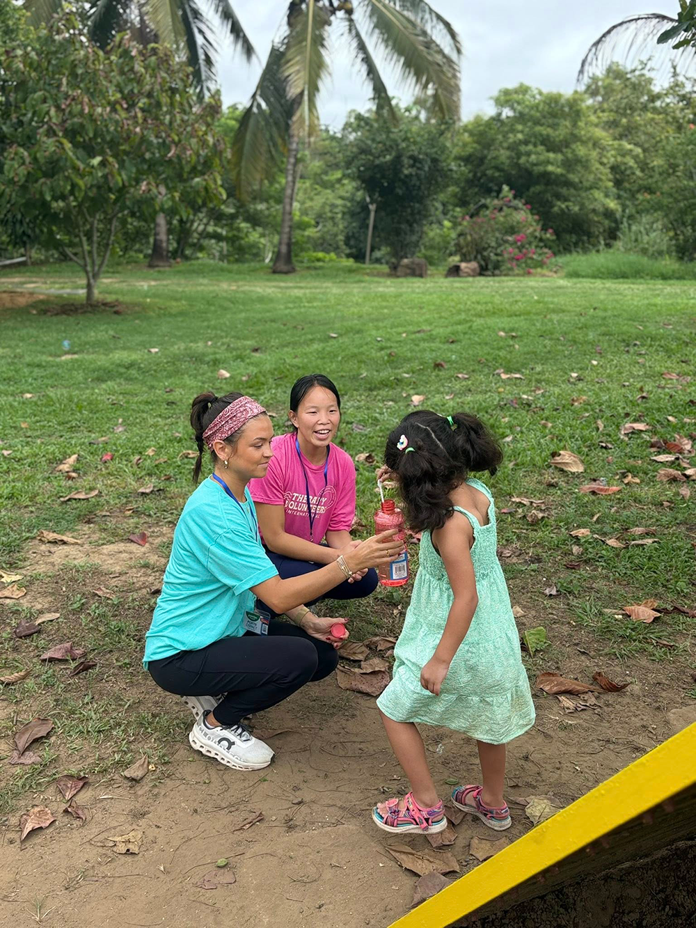 Students blowing bubbles with a child