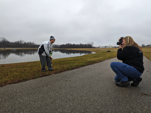woman taking photo of a woman with a dog along a river front