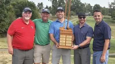 Members of the USI community pose with a trophy on the golf course