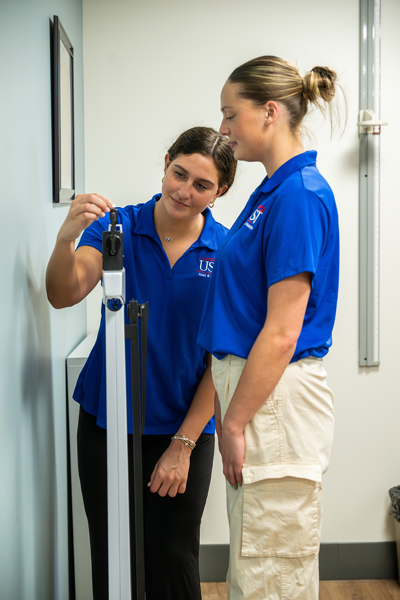 Students using scale to measure body weight in assessment room