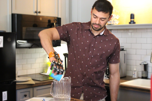 Student pouring water with arthritis simulator on hand