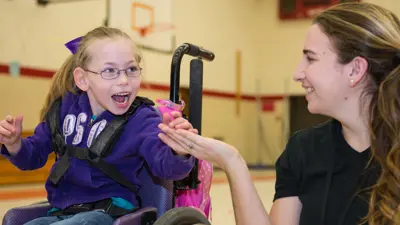 Teacher education student holds hands with a child in a wheelchair