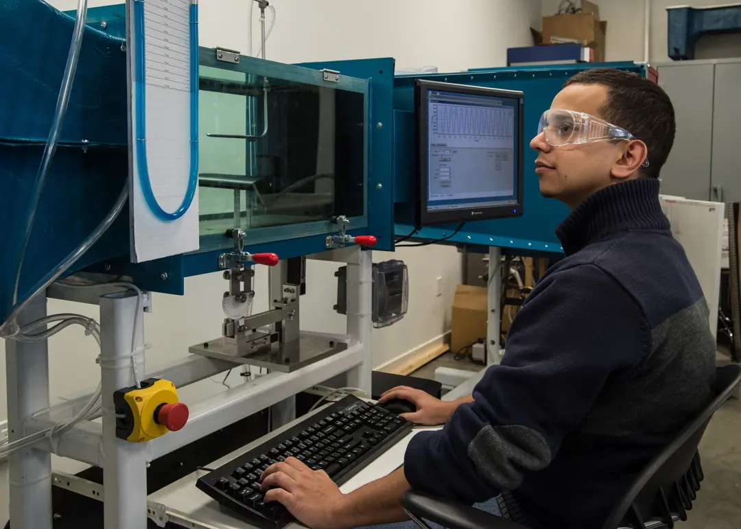USI engineering student wears safety glasses while he works on a computerized machine in a warehouse environment