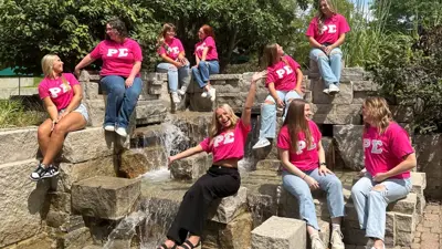 Group of girls pose in matching sorority shirts on the Rice Plaza Fountain
