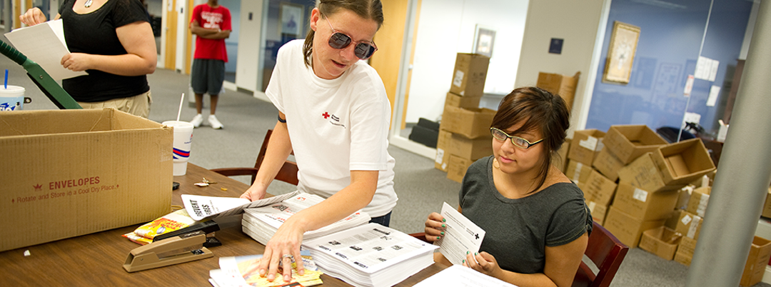 A couple of students sort and stuff mail for the American Red Cross