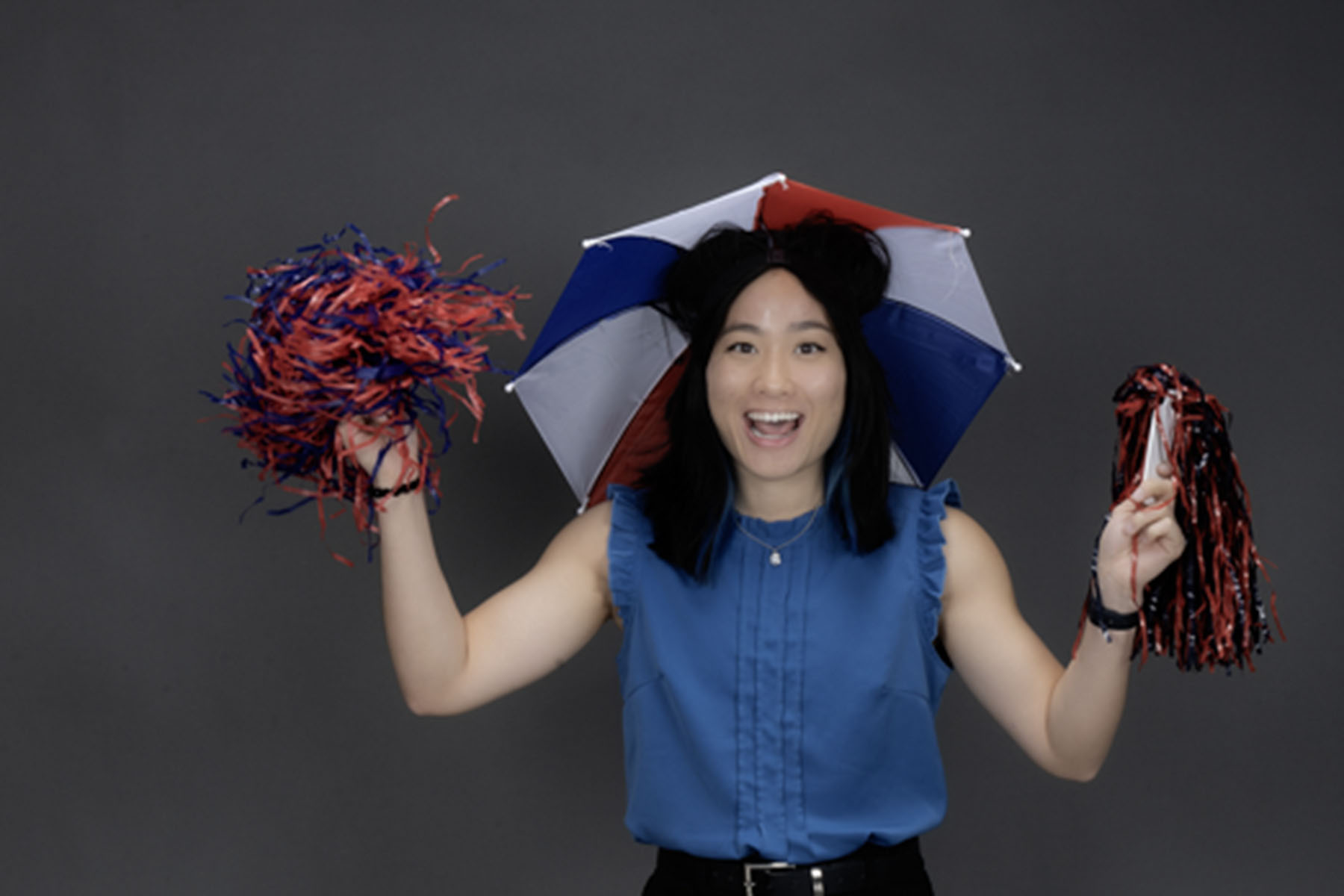 A member of the homecoming court, known for wearing an umbrella hat at new student orientation wears her umbrella hat and shakes pom poms.