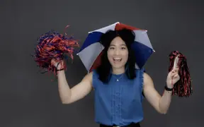 A member of the homecoming court, known for wearing an umbrella hat at new student orientation wears her umbrella hat and shakes pom poms.