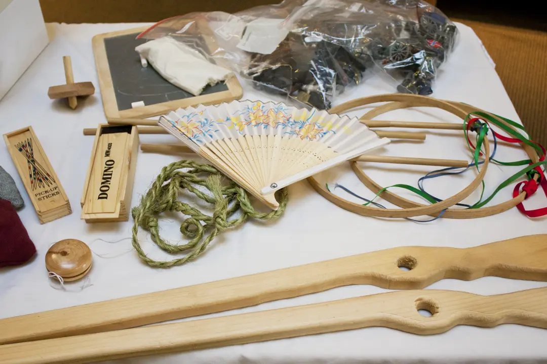Picture of handicrafts, including a wooden toy rifle, dominoes, a hand fan, and a yoyo