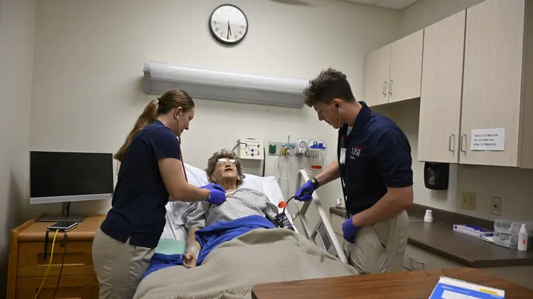 nursing students with a simulation patient in a hospital bed