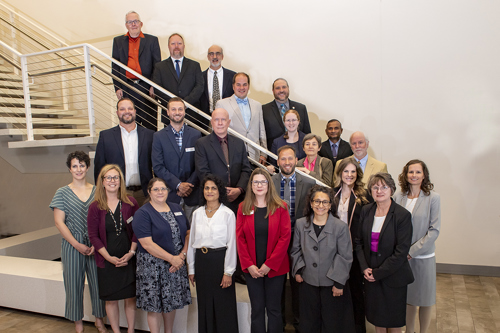 Faculty who have received tenure stand for a group photo on and around a staircase