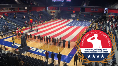 People gathered on the USI basketball court displaying a giant American flag
