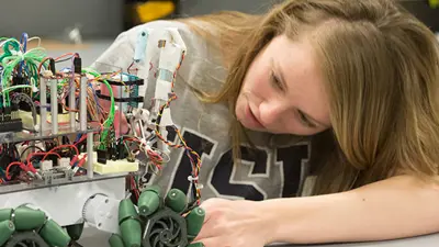 Female engineering student looking at complex electrical circuit
