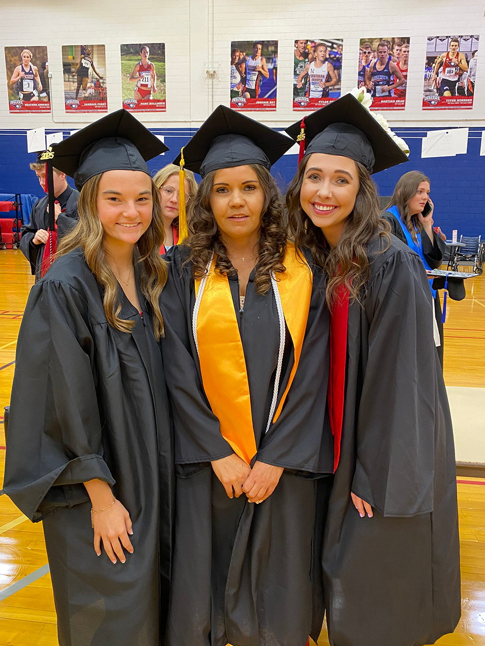 Three health administration students wearing graduation caps and gowns
