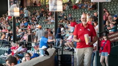 An Otters fan in USI attire walks with popcorn at Bosse Field