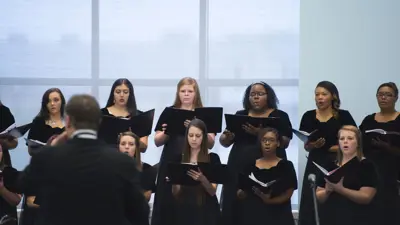 Women's Choir members and the director in formal wear at a performance