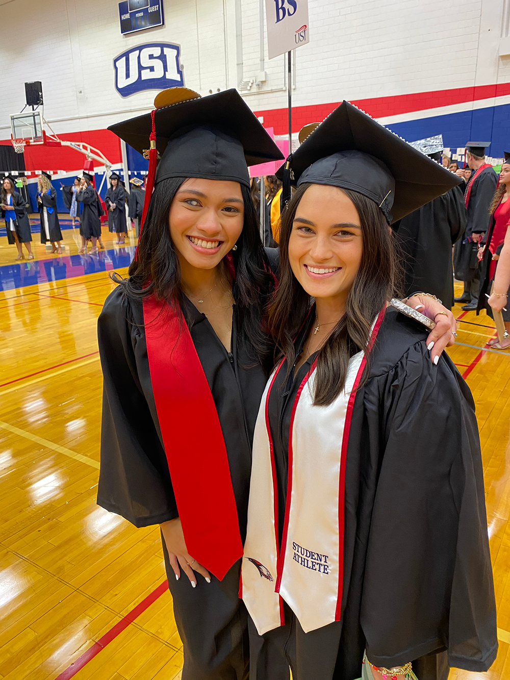 Two food and nutrition wearing graduation caps and gowns