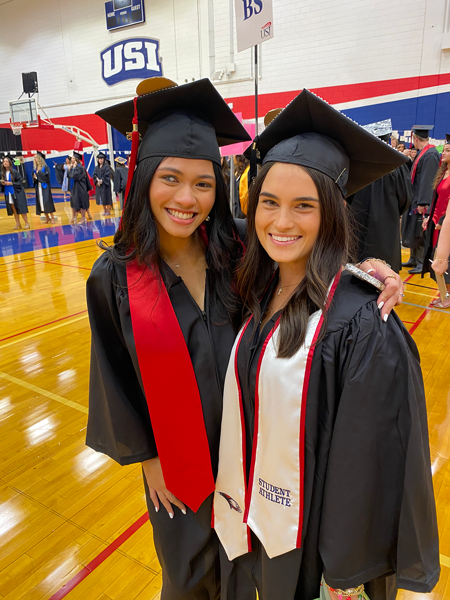Two food and nutrition wearing graduation caps and gowns