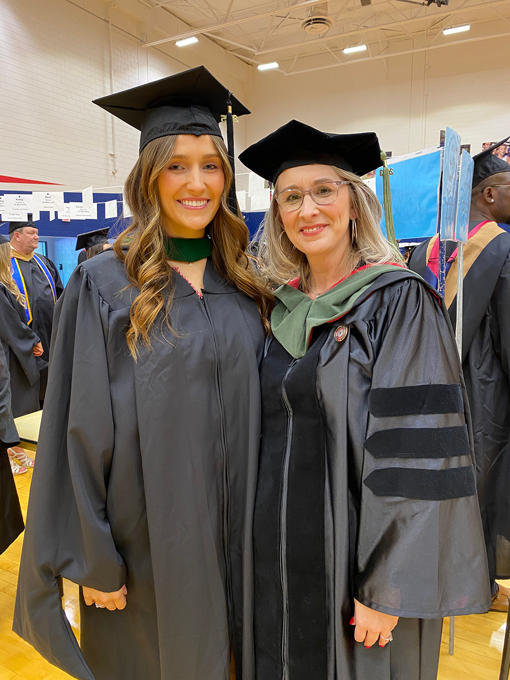 MHA student and faculty member in cap and gown